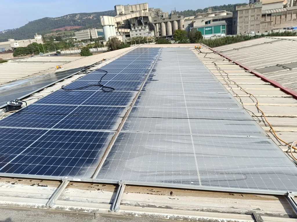 Coberta industrial amb panells solars nets i bruts — resultat de la neteja professional