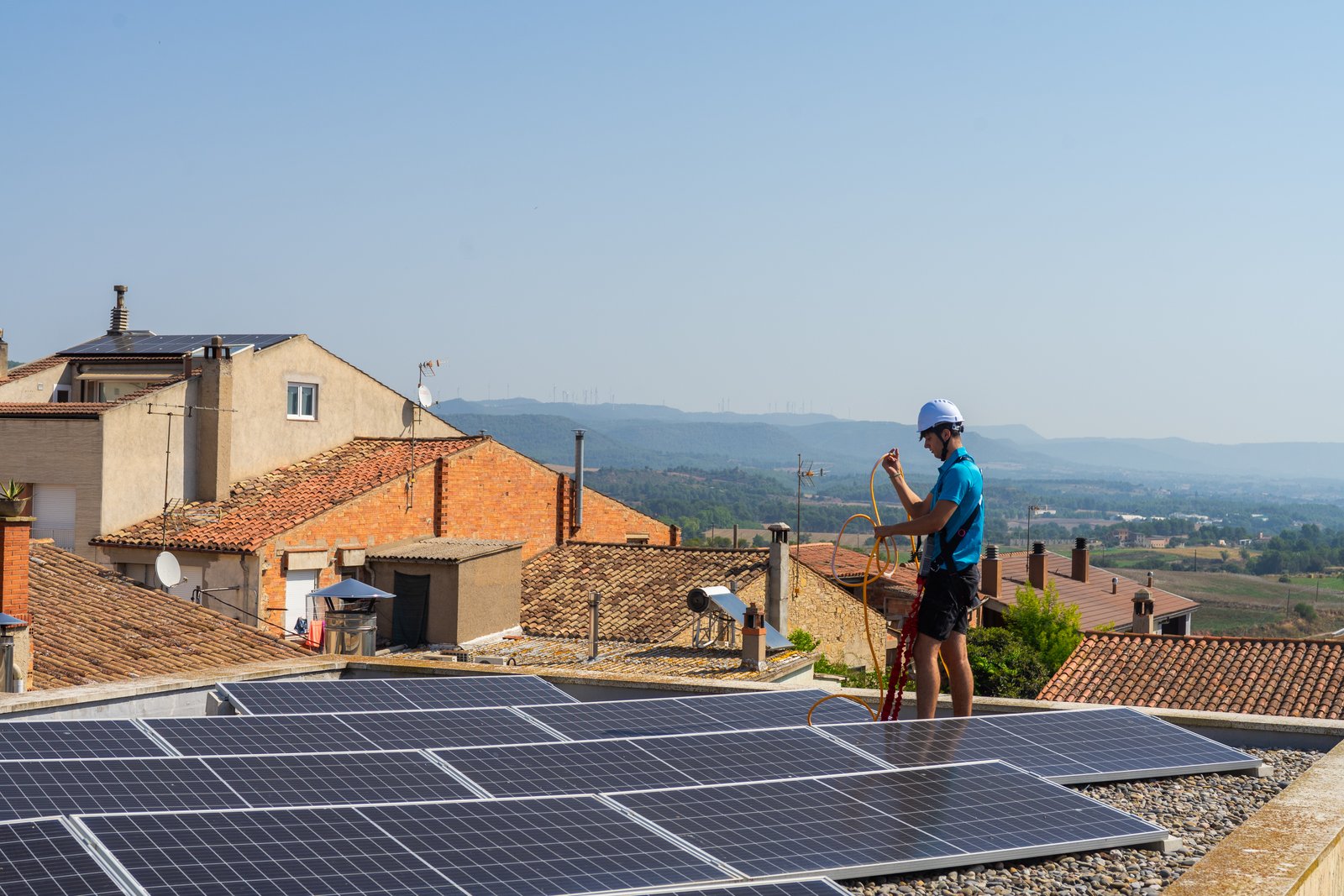 Tècnic de Neteja Solar preparant equip a la teulada amb paisatge rural català
