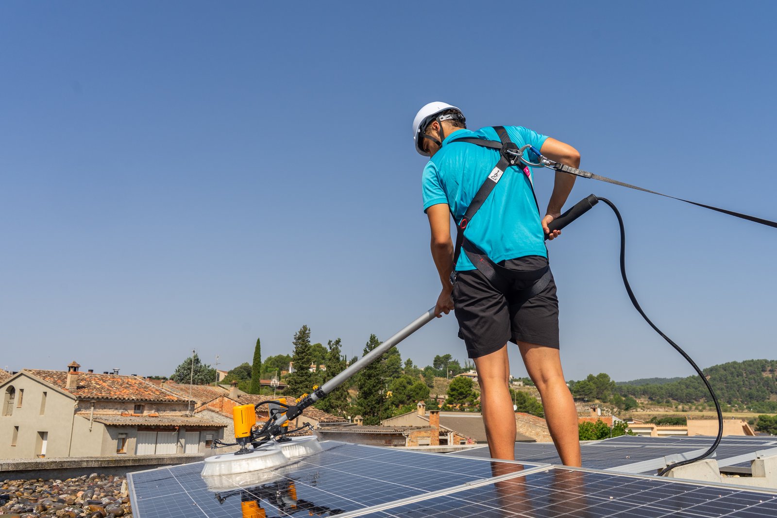 Técnico de Neteja Solar limpiando paneles solares con equipo profesional en tejado catalán