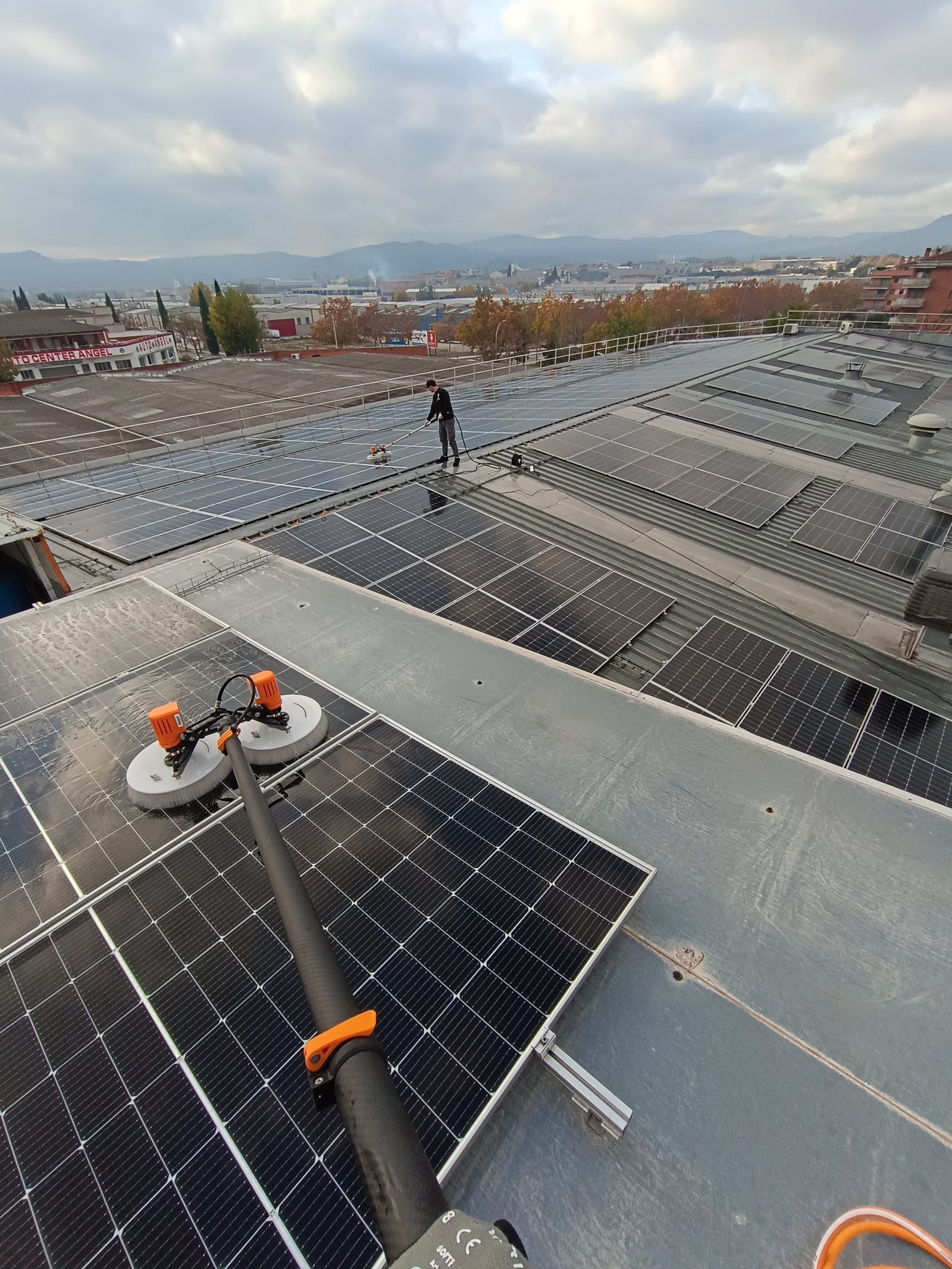 Limpieza de instalación solar industrial en gran cubierta con paisaje urbano de fondo — Cataluña