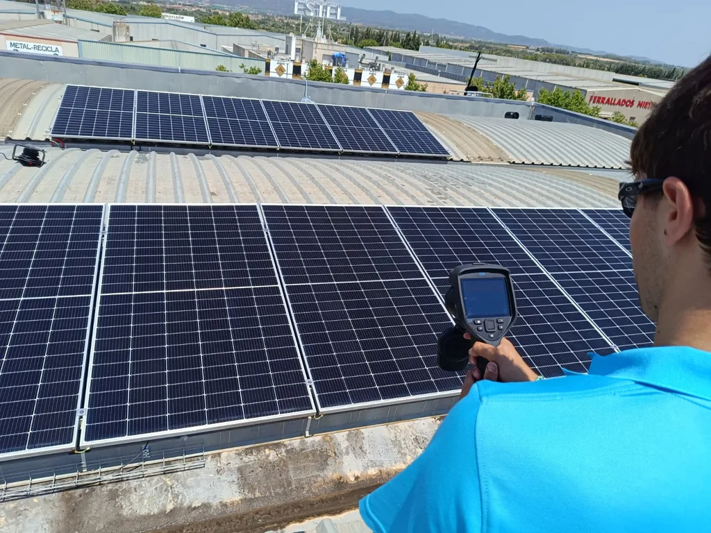 Tècnic fent una inspecció termogràfica de panells solars amb càmera FLIR de mà en una coberta de Catalunya